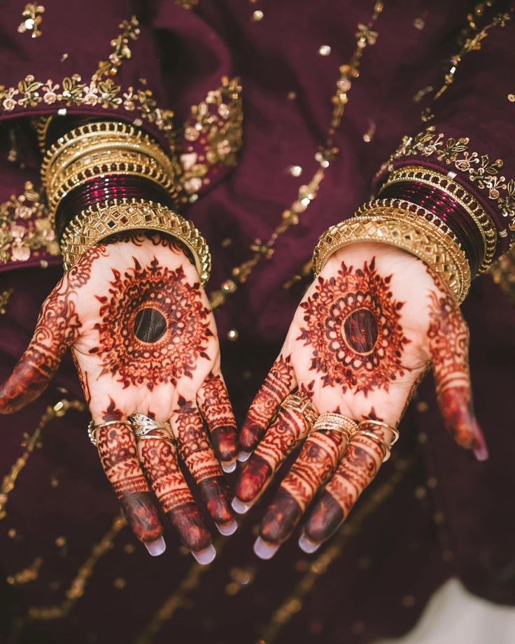 Close-up of bridal hands with intricate mehendi and gold bangles